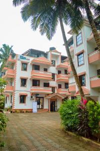 een groot gebouw met palmbomen ervoor bij Hotel Siesta De Goa in Varca