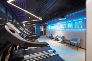 a gym with a row of exercise machines and a sign at The Quarter Silom by UHG in Bangkok