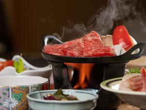 
a pan filled with meat and vegetables on top of a stove top at Shimaya in Yamanouchi
