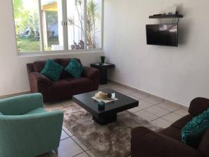 a living room with couches and a table and a tv at House with Pool near the Beach CTE69 in Mezcales