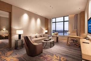 a living room with a couch and a tv at Howard Johnson by Wyndham Jimei Lake Plaza Xiamen in Xiamen