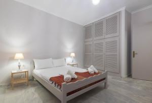 ein weißes Schlafzimmer mit einem Bett und zwei Nachttischen in der Unterkunft The Lofos Studios in Alykes