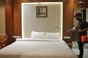 a man standing next to a bed in a room at Hotel Priya in Kottakkal