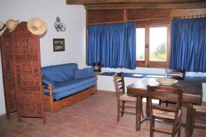un soggiorno con tavolo e divano blu di Case Mare - terrazzi panoramici e ampio giardino a Santa Marina Salina