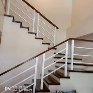 a staircase in a house with wood and white railings at Creys Condo 3 at Pico De Loro Cove in Nasugbu