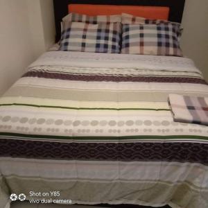 a bed with plaid pillows on top of it at Creys Condo 3 at Pico De Loro Cove in Nasugbu