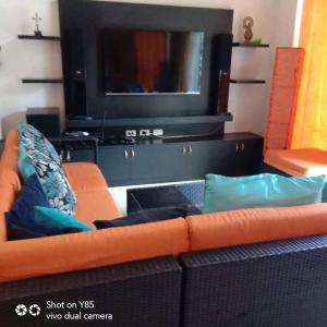 a living room with an orange couch and a flat screen tv at Creys Condo 3 at Pico De Loro Cove in Nasugbu