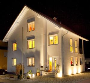 Ferienwohnung Familie Buchner في Großheubach: منزل أبيض ونوافذ مضاءة في الليل