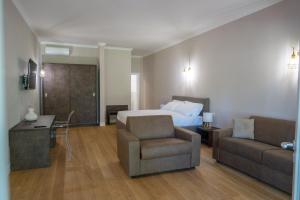 a hotel room with a bed and a couch and a chair at La Tenuta di Rocca Bruna Country Resort in Tivoli