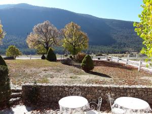 a garden with two tables and a fence and mountains at La Bastide des Pins in La Bastide