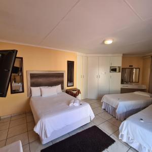 a hotel room with two beds and a tv at Ethen Guesthouse in Polokwane