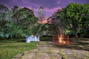 eine Feuerstelle in einem Feld mit einer Gruppe von Tischen in der Unterkunft Club Mahindra Madikeri, Coorg in Madikeri