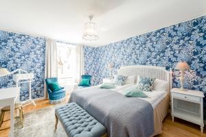 - une chambre avec du papier peint bleu, un lit et une chaise dans l'établissement Krusenberg Herrgård, à Krusenberg