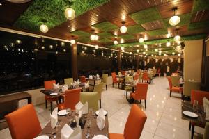 奇陶尔加尔Hotel The Grand Chittor, Chittorgarh的有桌椅和灯的餐厅