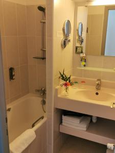 a bathroom with a sink and a tub and a mirror at Logis Le Gavrinis in Baden