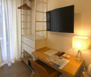 Zimmer mit einem Schreibtisch und einem TV an der Wand in der Unterkunft Real Rooms in La Spezia