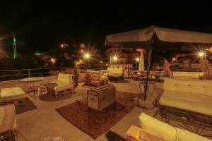 a patio with chairs and an umbrella at night at Harkasos Cave Hotel in Urgup