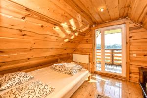 a log cabin bedroom with two beds and a window at Vila Karališkis in Karališkiai