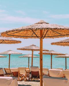 een groep stoelen en parasols op een strand bij Georgalas Sun Beach Resort in Nea Kalikratia