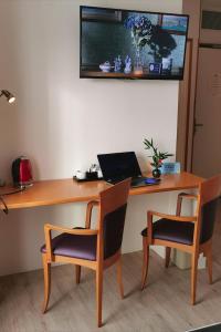a desk with two chairs and a laptop on it at Logis Le Gavrinis in Baden