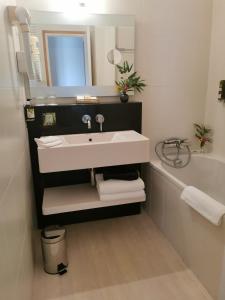 a bathroom with a sink and a bath tub at Logis Le Gavrinis in Baden