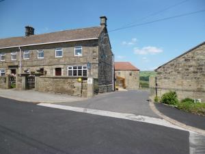 un antiguo edificio de piedra con una carretera delante de él en Padley Farm, en Bradfield