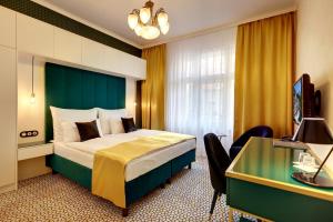 カルロヴィ・ヴァリにあるArt Deco WOLKER by ASTORIA Hotel & Medical Spaのベッドとデスクが備わるホテルルームです。