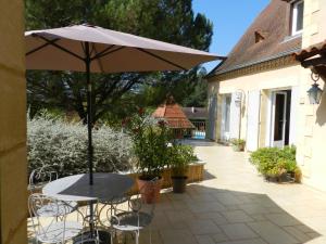 a table with an umbrella on a patio at La Sembelie in Carsac-Aillac