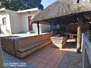 a patio with a bench and a thatch roof at Lytton Cresent B&B in Pinetown