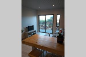 sala de estar con mesa de madera y ventana grande en Lovely brand new flat near restaurants and beach with solar - free wifi and DSTV, en Cape St. Francis