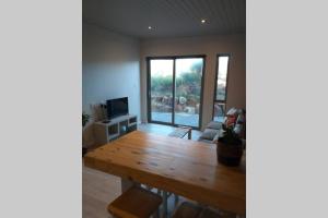 a living room with a wooden table and a large window at Lovely brand new flat near restaurants and beach with solar - free wifi and DSTV in Cape St Francis