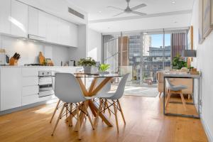 una cucina con armadi bianchi, tavolo e sedie di Waterloo St Apartments by Urban Rest a Sydney