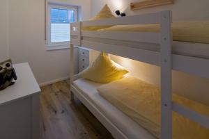 Etagenbett mit gelbem Kissen auf dem unteren Etagenbett in der Unterkunft Südwester in Dornumersiel