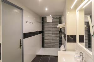 a white bathroom with a shower and a sink at Hôtel Spunta Di Mare in Ajaccio