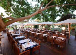 a restaurant with tables and chairs and umbrellas at UNAHOTELS Club Hotel Ancora in Stintino