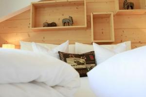 a bedroom with white pillows on a bed at Hotel Valpudra in Selva di Val Gardena
