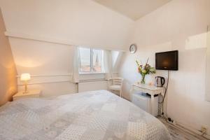 a bedroom with a bed and a tv on the wall at Blankebil Rooms in Zandvoort