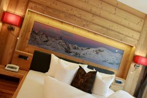 - une chambre dotée d'un lit blanc avec une photo sur le mur dans l'établissement Hotel Valpudra, à Selva di Val Gardena