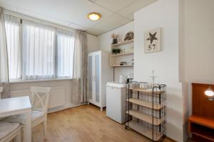 eine Küche mit einem weißen Kühlschrank und einem Tisch in der Unterkunft Blankebil Rooms in Zandvoort