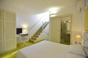 a bedroom with a bed and a desk and a staircase at UNAHOTELS Club Hotel Ancora in Stintino
