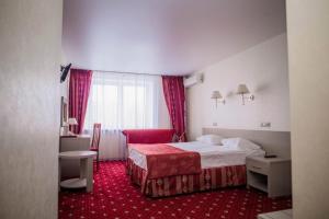 トリヤッチにあるホテル アマクス ユビレーナヤの赤いカーペット敷きの客室で、ベッド1台が備わります。