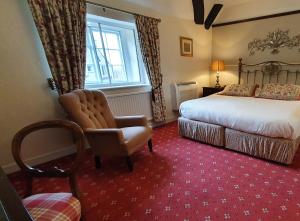a bedroom with a bed and a chair and a window at Stow Lodge Hotel in Stow on the Wold