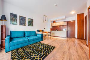 克里尼查謨爾斯卡的住宿－Apartamenty Sun & Snow Continental，一间带蓝色沙发的客厅和一间厨房