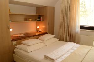 um quarto com uma cama com almofadas brancas e uma janela em Vila Park B&B - Adults Only em Bohinj