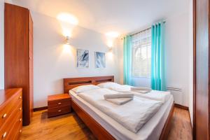 a bedroom with a bed with white sheets and a window at Apartamenty Sun & Snow Continental in Krynica Morska
