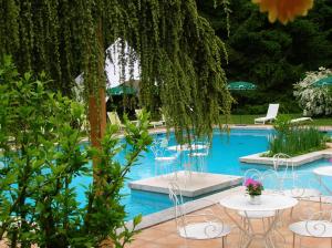 a swimming pool with tables and chairs and trees at La Chrissandière in La Balme-de-Sillingy