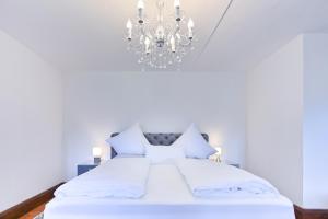 a bedroom with a white bed with a chandelier at Schloss zu Hopferau in Hopferau