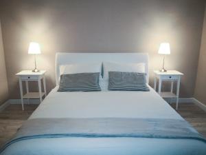 een groot wit bed met 2 nachtkastjes en 2 lampen bij La casa di Fabia - Home suite in Messina