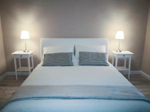 - un grand lit blanc avec 2 tables de chevet et 2 lampes dans l'établissement La casa di Fabia - Home suite, à Messina