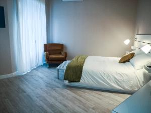 1 dormitorio con 1 cama y 1 silla en La casa di Fabia - Home suite, en Messina